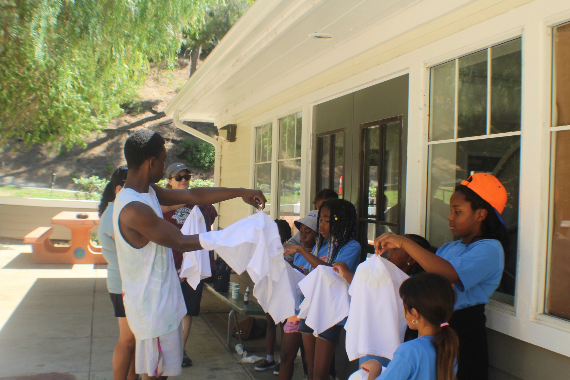 Camp Hollywoodland Staff shows children how to tie day their camp shirts